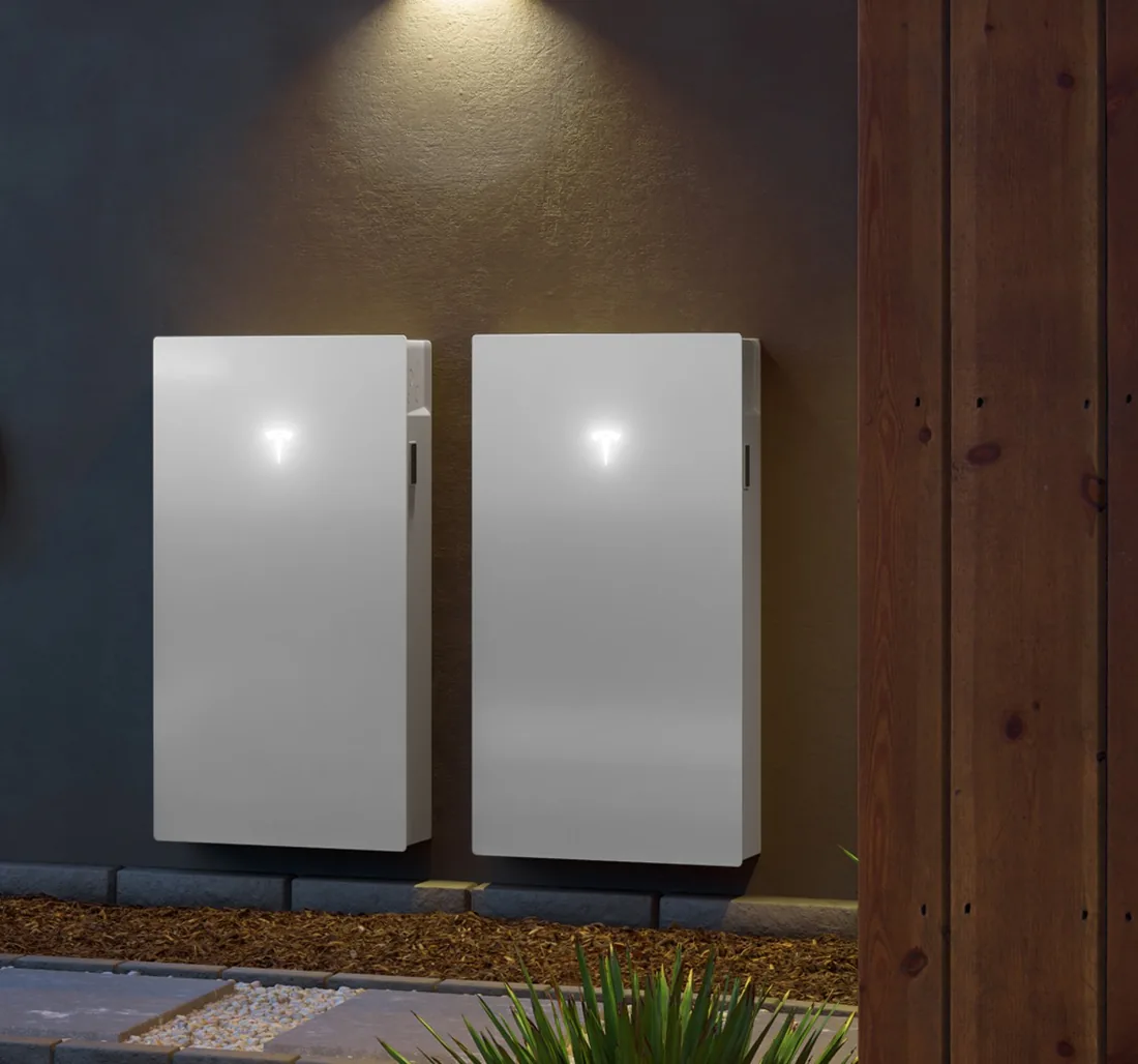 Two Tesla Powerwall units mounted side by side on a dark exterior wall